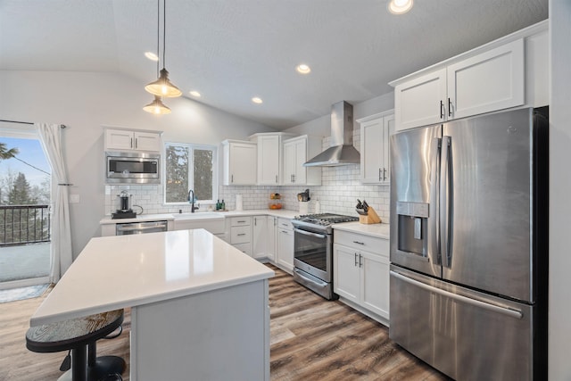 kitchen featuring sink, wall chimney exhaust hood, lofted ceiling, decorative backsplash, and appliances with stainless steel finishes