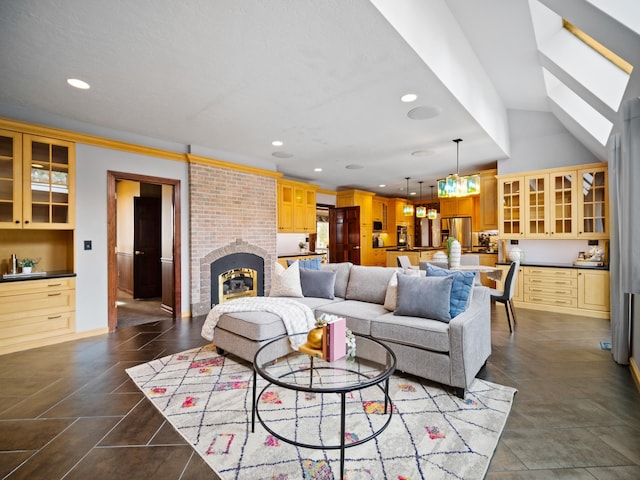 living room with a chandelier, a brick fireplace, and ornamental molding