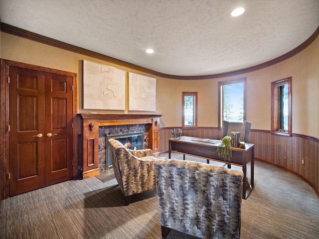 carpeted living room featuring wooden walls, a high end fireplace, and a textured ceiling