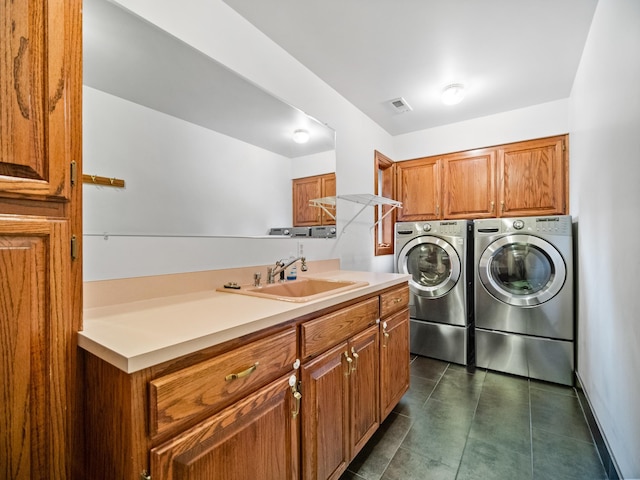 clothes washing area featuring separate washer and dryer, sink, dark tile patterned floors, and cabinets