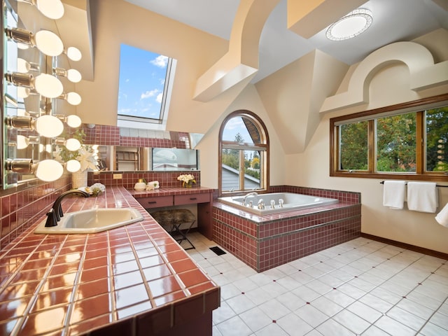 bathroom featuring vanity, a skylight, tile patterned flooring, a towering ceiling, and tiled bath