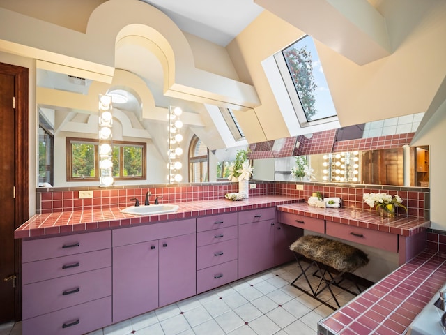 bathroom with decorative backsplash, a skylight, tile patterned floors, vanity, and high vaulted ceiling