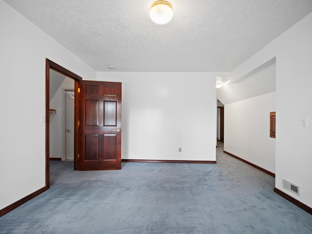 carpeted spare room featuring a textured ceiling and vaulted ceiling