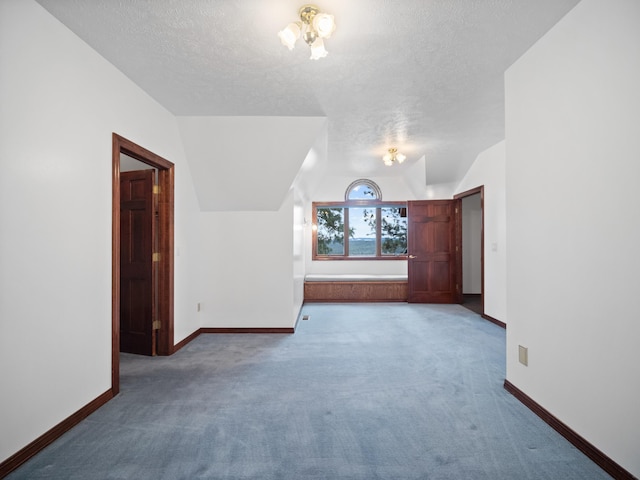 additional living space featuring carpet flooring, a notable chandelier, lofted ceiling, and a textured ceiling