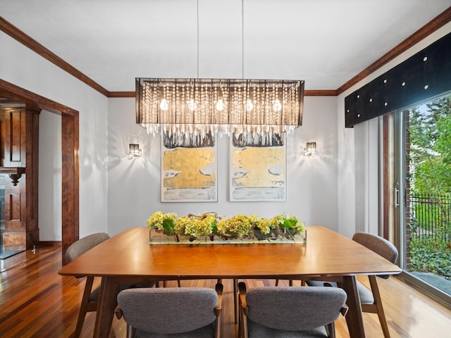 dining area with crown molding, an inviting chandelier, and hardwood / wood-style flooring