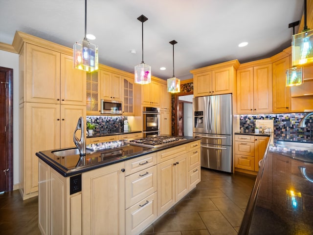 kitchen with light brown cabinets, sink, hanging light fixtures, stainless steel appliances, and an island with sink