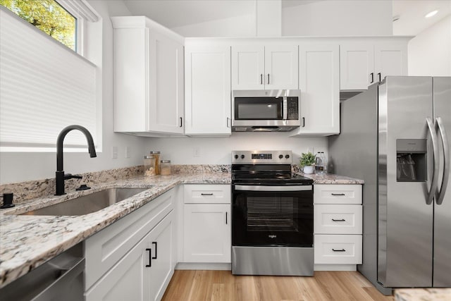 kitchen featuring light stone countertops, appliances with stainless steel finishes, white cabinetry, and sink