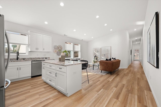 kitchen featuring white cabinets, a breakfast bar, a center island, and appliances with stainless steel finishes