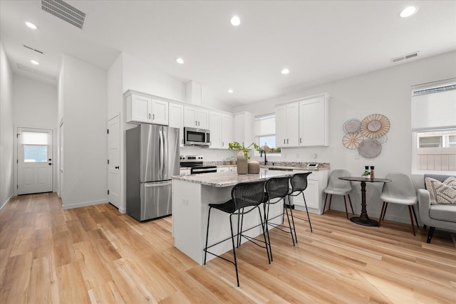 kitchen with white cabinets, a kitchen breakfast bar, stainless steel appliances, and a kitchen island