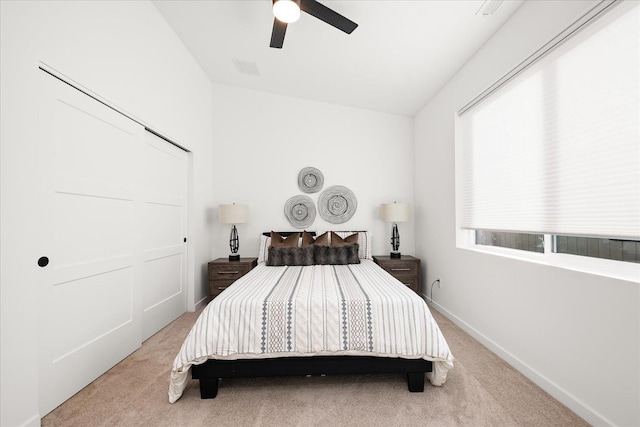 bedroom with ceiling fan, light colored carpet, and a closet