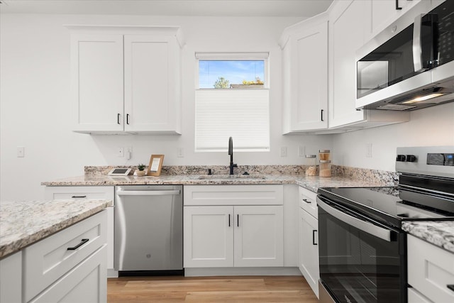 kitchen featuring white cabinets, light stone counters, sink, and appliances with stainless steel finishes