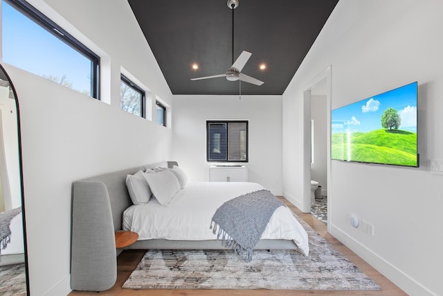 bedroom with hardwood / wood-style floors, ceiling fan, high vaulted ceiling, and ensuite bath