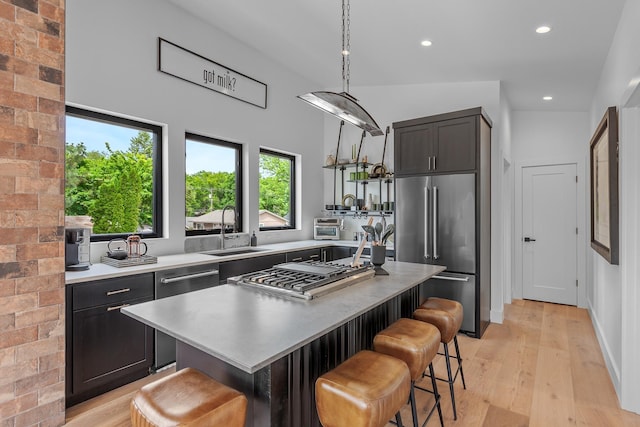 kitchen with high end refrigerator, a breakfast bar, a center island, light hardwood / wood-style floors, and hanging light fixtures