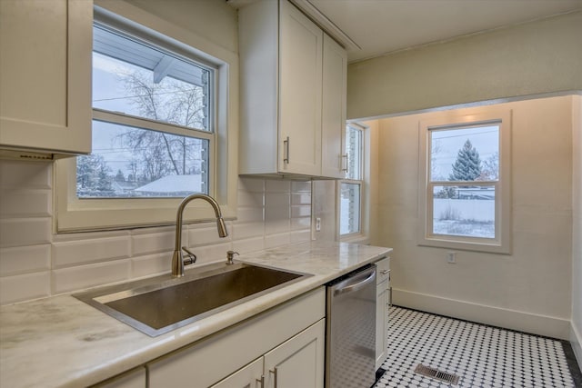 kitchen featuring dishwasher, white cabinetry, decorative backsplash, and sink