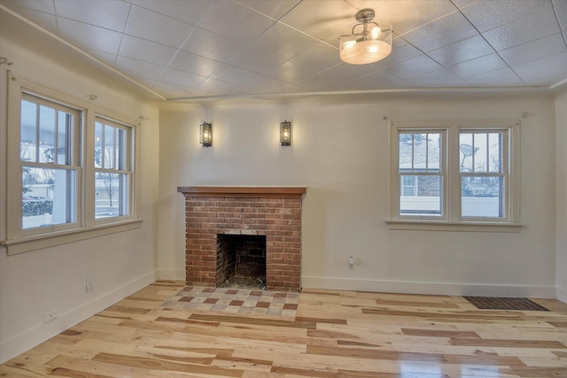 unfurnished living room featuring light hardwood / wood-style flooring and a brick fireplace