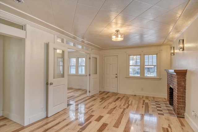 foyer entrance featuring a fireplace and light hardwood / wood-style flooring