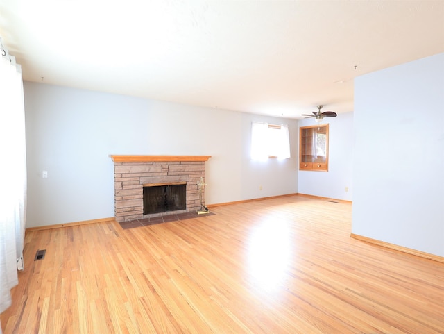 unfurnished living room featuring a stone fireplace, light hardwood / wood-style floors, and ceiling fan