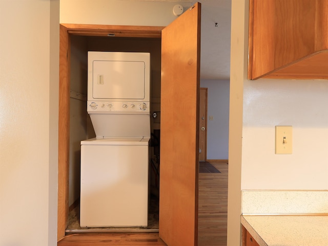 washroom with stacked washer and dryer and light hardwood / wood-style floors