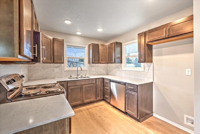 kitchen featuring appliances with stainless steel finishes, light hardwood / wood-style flooring, tasteful backsplash, and sink