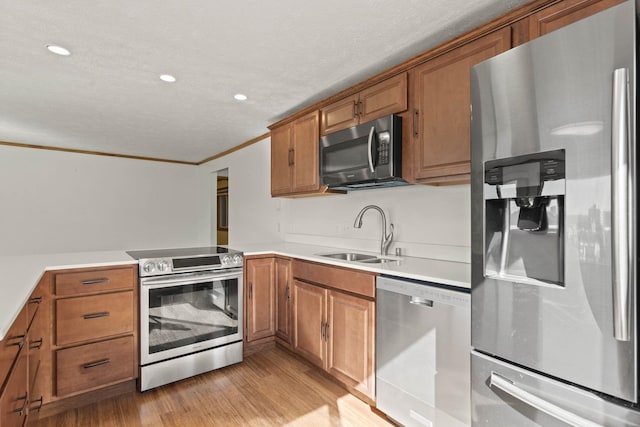 kitchen with kitchen peninsula, light wood-type flooring, appliances with stainless steel finishes, ornamental molding, and sink