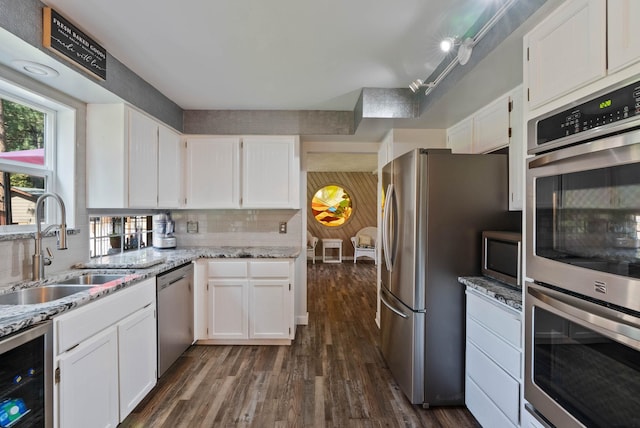 kitchen with white cabinets, beverage cooler, light stone countertops, and stainless steel appliances