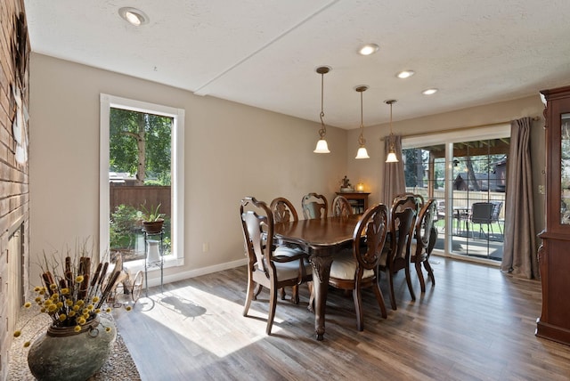 dining space featuring a textured ceiling, wood-type flooring, and plenty of natural light