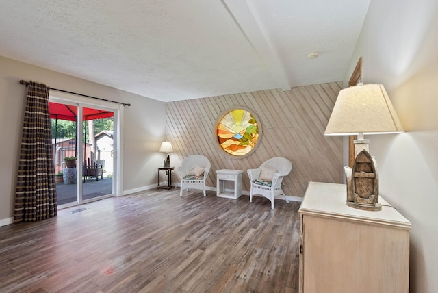 living area featuring dark wood-type flooring, a textured ceiling, and wood walls