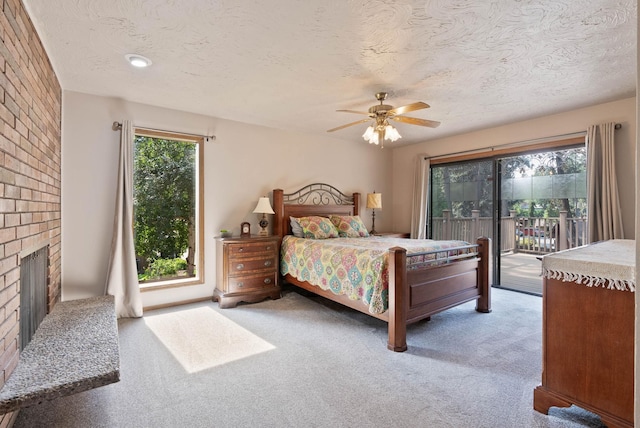 carpeted bedroom with ceiling fan, a fireplace, a textured ceiling, and access to exterior