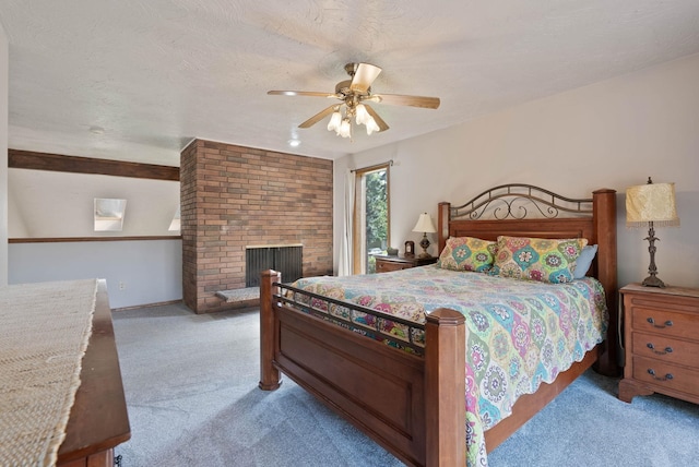 bedroom featuring light carpet, ceiling fan, a textured ceiling, and a fireplace