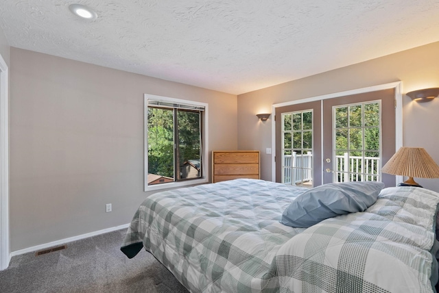 carpeted bedroom with a textured ceiling, french doors, and access to exterior