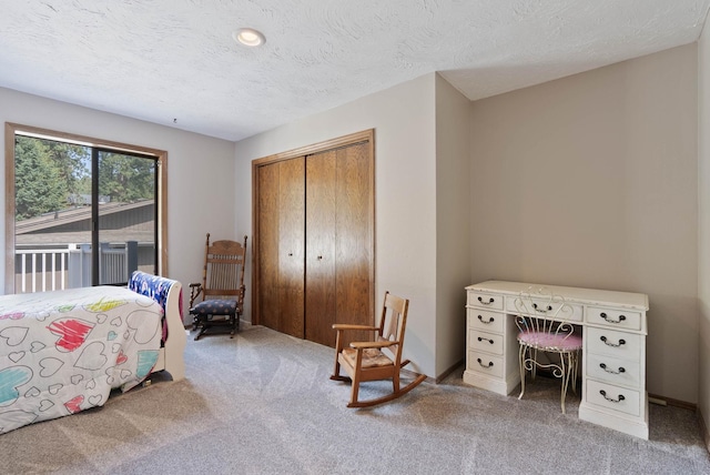 bedroom featuring carpet flooring, a closet, a textured ceiling, and access to exterior