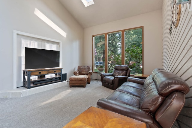 carpeted living room featuring high vaulted ceiling and a skylight