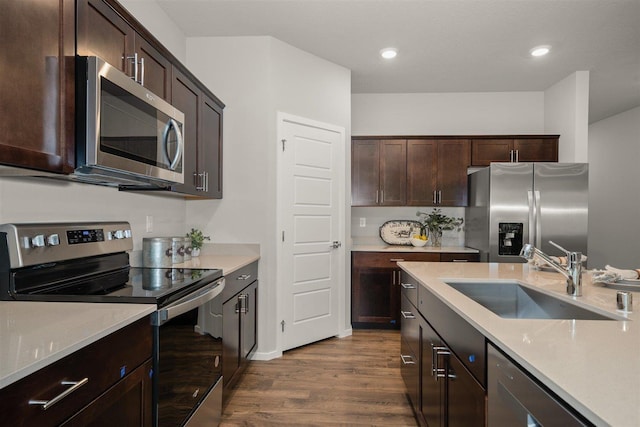 kitchen with stainless steel appliances, dark brown cabinetry, sink, and dark hardwood / wood-style floors