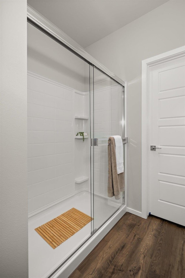 bathroom with hardwood / wood-style flooring and a shower with shower door