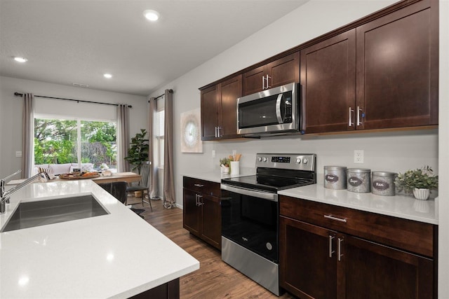 kitchen with stainless steel appliances, dark brown cabinets, dark hardwood / wood-style flooring, and sink