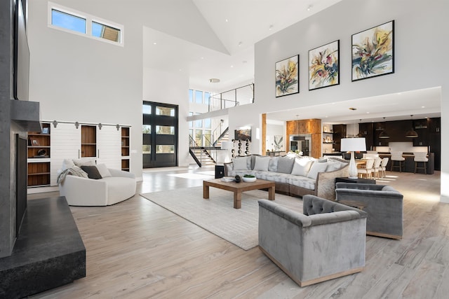 living room featuring light wood-type flooring, high vaulted ceiling, and a barn door