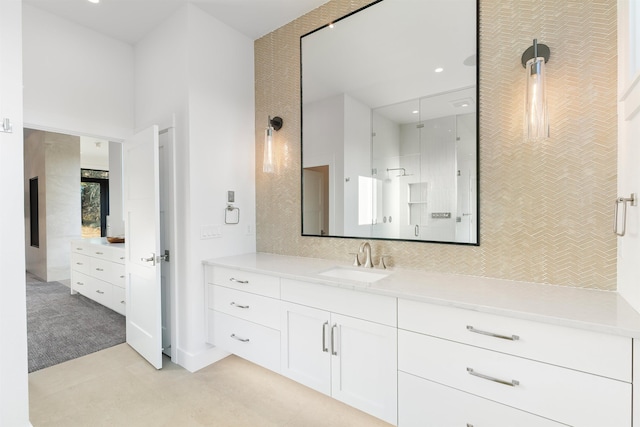 bathroom with a high ceiling, backsplash, walk in shower, and vanity