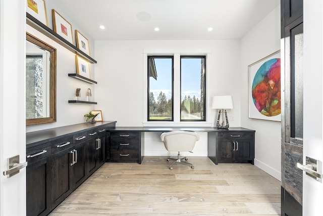 home office with built in desk and light hardwood / wood-style floors