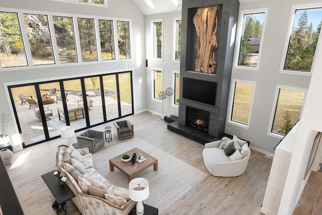 living room with a high ceiling, light wood-type flooring, and a large fireplace