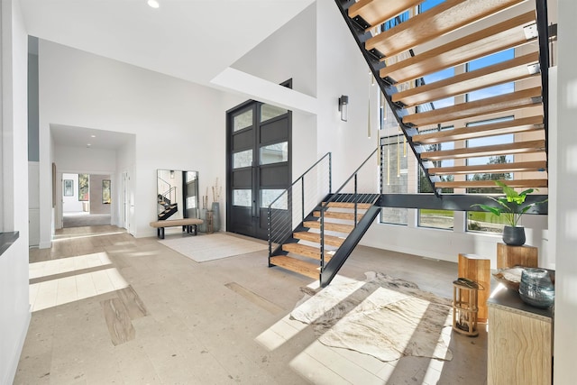 foyer entrance featuring a towering ceiling and a healthy amount of sunlight