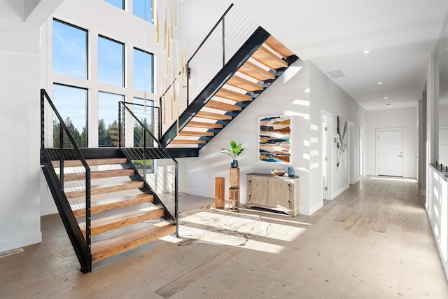 stairs featuring a towering ceiling and wood-type flooring