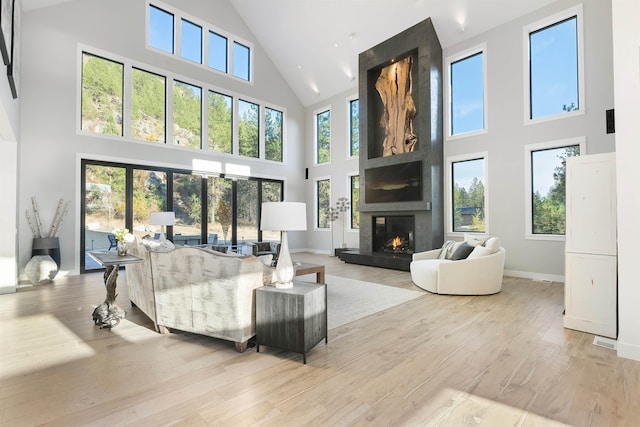 living room with light wood-type flooring and a towering ceiling