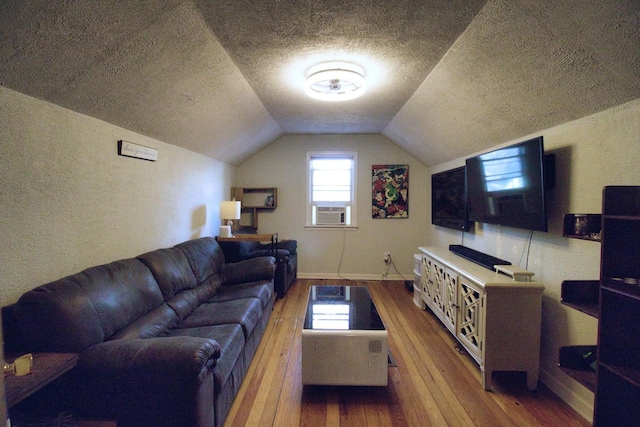 living room with lofted ceiling, cooling unit, hardwood / wood-style flooring, and a textured ceiling