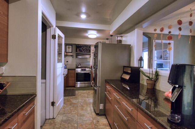 kitchen with appliances with stainless steel finishes and dark stone counters