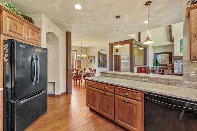 kitchen with light stone counters, light wood-type flooring, pendant lighting, decorative backsplash, and black appliances