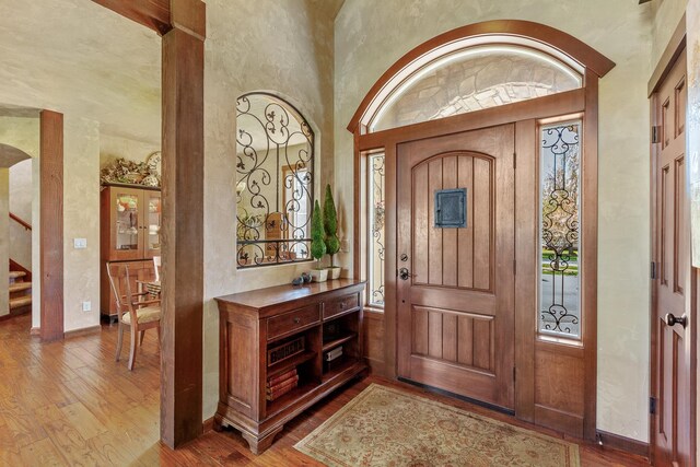 entryway with a high ceiling, a wealth of natural light, and wood-type flooring