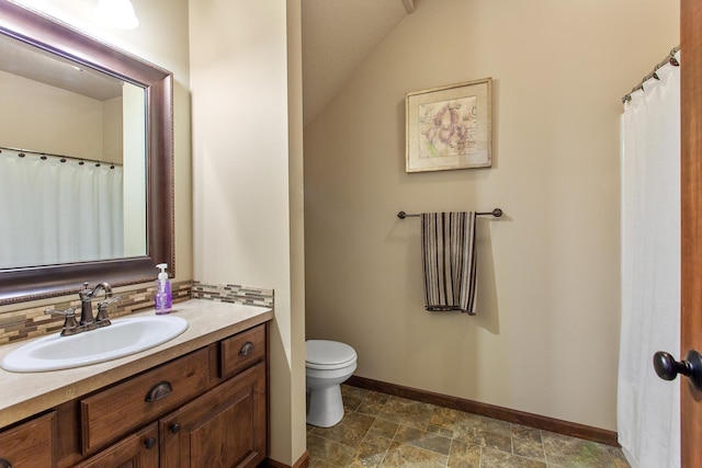 bathroom featuring toilet, vanity, lofted ceiling, and tasteful backsplash