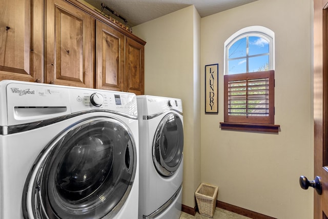 laundry room featuring a textured ceiling, washing machine and dryer, and cabinets