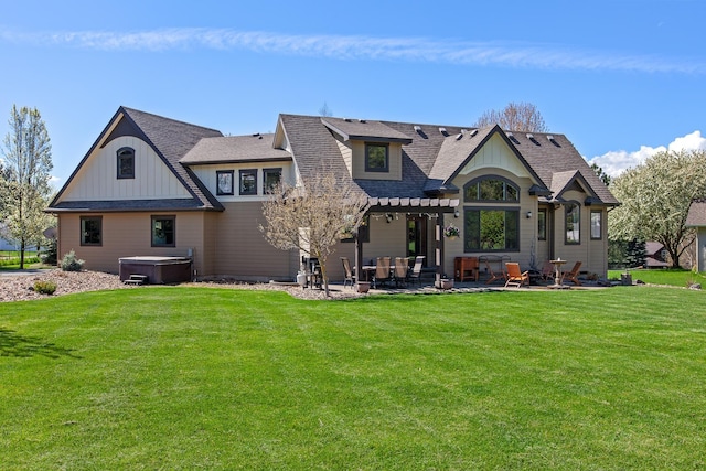 rear view of property with a patio, a yard, and a hot tub