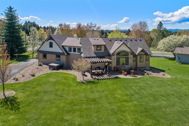 back of house with a hot tub, outdoor lounge area, a patio, and a lawn